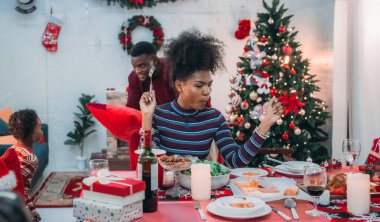 Siyah ailenin Noel yemeğinin keyfini çıkardığı canlı bir sahne, Noel mevsiminin sıcaklığını ve neşesini, güzel dekore edilmiş masaların etrafında yakalıyor, anne, baba ve oğulun özel anlarını paylaştığı.
