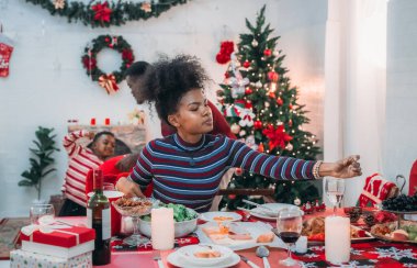 Siyah ailenin Noel yemeğinin keyfini çıkardığı canlı bir sahne, Noel mevsiminin sıcaklığını ve neşesini, güzel dekore edilmiş masaların etrafında yakalıyor, anne, baba ve oğulun özel anlarını paylaştığı.