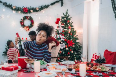 Siyah ailenin Noel yemeğinin keyfini çıkardığı canlı bir sahne, Noel mevsiminin sıcaklığını ve neşesini, güzel dekore edilmiş masaların etrafında yakalıyor, anne, baba ve oğulun özel anlarını paylaştığı.