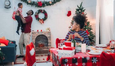 Siyah ailenin Noel yemeğinin keyfini çıkardığı canlı bir sahne, Noel mevsiminin sıcaklığını ve neşesini, güzel dekore edilmiş masaların etrafında yakalıyor, anne, baba ve oğulun özel anlarını paylaştığı.