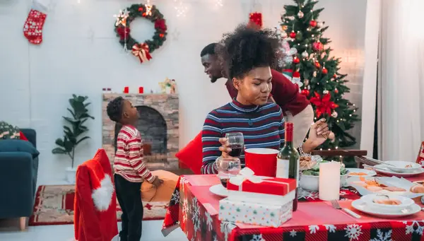Siyah ailenin Noel yemeğinin keyfini çıkardığı canlı bir sahne, Noel mevsiminin sıcaklığını ve neşesini, güzel dekore edilmiş masaların etrafında yakalıyor, anne, baba ve oğulun özel anlarını paylaştığı.