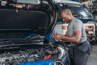Yetenekli bir otomotiv teknisyeni, garaj atölyesindeki bir aracın havalandırma sistemini tanımlamak ve hizmet vermek için manifold göstergeleri kullanır..