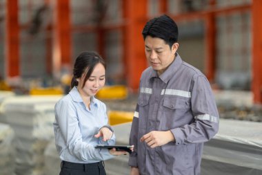 Profesyonel bir erkek ve kadın dijital tablet üzerinde iş birliği yaparak, sürdürülebilir iyileştirme için ISO standartlarını yükseltmek için bir metal levha fabrikasının hareketli ortamında iş birliği yapıyorlar..