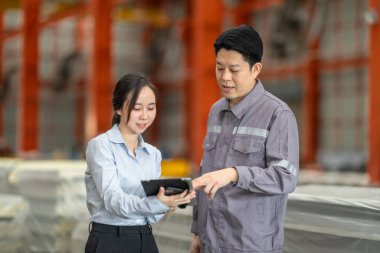 Profesyonel bir erkek ve kadın dijital tablet üzerinde iş birliği yaparak, sürdürülebilir iyileştirme için ISO standartlarını yükseltmek için bir metal levha fabrikasının hareketli ortamında iş birliği yapıyorlar..