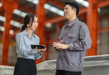 Profesyonel bir erkek ve kadın dijital tablet üzerinde iş birliği yaparak, sürdürülebilir iyileştirme için ISO standartlarını yükseltmek için bir metal levha fabrikasının hareketli ortamında iş birliği yapıyorlar..