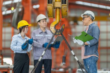 Aralarında bir kadın ve iki erkek profesyonelin de bulunduğu bir mühendis ekibi, metal levha fabrikasındaki ekipmanların kaldırılması, uyumluluk ve operasyonel verimliliği sağlama amaçlı bir güvenlik denetimi yürütüyor..