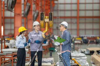 Aralarında bir kadın ve iki erkek profesyonelin de bulunduğu bir mühendis ekibi, metal levha fabrikasındaki ekipmanların kaldırılması, uyumluluk ve operasyonel verimliliği sağlama amaçlı bir güvenlik denetimi yürütüyor..