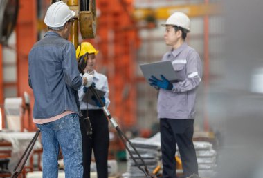 Aralarında bir kadın ve iki erkek profesyonelin de bulunduğu bir mühendis ekibi, metal levha fabrikasındaki ekipmanların kaldırılması, uyumluluk ve operasyonel verimliliği sağlama amaçlı bir güvenlik denetimi yürütüyor..