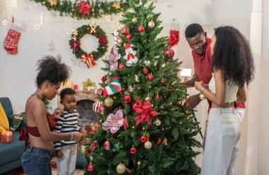 Neşeli Siyah ailesi Noel ağacını süsleyerek ve birlikte oynayarak, Noel süslemeleri, kahkahalar, sıcaklıklar, Noel neşesi ve beraberliğinin özünü yakalayarak tatil sezonunun tadını çıkarıyor.