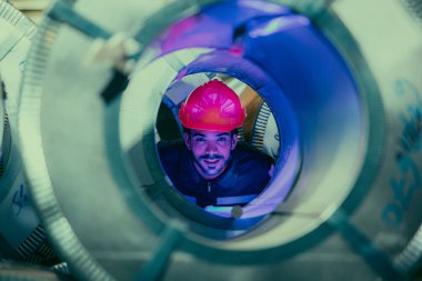 Mühendis, metal levha fabrikasındaki detaylara dikkat ederek üretim hattındaki ekipmanları yakından inceliyor..