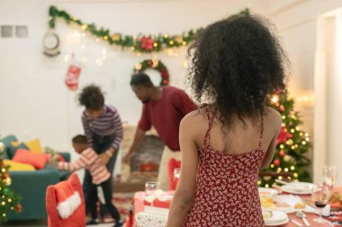 Tatil döneminde siyahi aile toplantısı, Noel ağacı, çelenk ve şenlikli süslemelerle süslenmiş güzel bir oturma odası. Sıcak atmosfer aşkın özünü yakalar, birlikteliği..