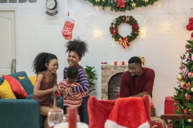 Tatil döneminde siyahi aile toplantısı, Noel ağacı, çelenk ve şenlikli süslemelerle süslenmiş güzel bir oturma odası. Sıcak atmosfer aşkın özünü yakalar, birlikteliği..