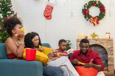 Tatil döneminde siyahi aile toplantısı, Noel ağacı, çelenk ve şenlikli süslemelerle süslenmiş güzel bir oturma odası. Sıcak atmosfer aşkın özünü yakalar, birlikteliği..