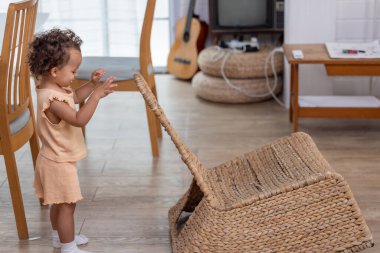 Kıvırcık saçlı bir çocuk, ahşap mobilya ve gitarla dolu parlak bir oturma odasında örülmüş bir sepetle meşgul oluyor. Hava sıcak ve davetkar..