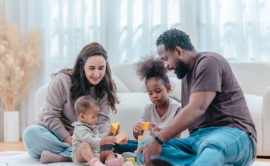 Çeşitli ailelerin birlikte oturma odasında kaliteli zaman geçirmesi çok iç açıcı bir manzara. Grupta ebeveynler ve iki çocuk, modern aile ortamında sevgi, bağlantı ve birliktelik sergileniyor.