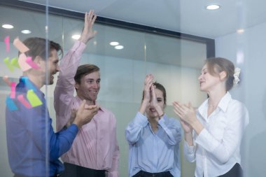 Ofisteki bir grup profesyonel başarıları alkış ve gülümsemeyle kutluyor. Pozitif atmosfer takım çalışması, motivasyon, başarı, işbirliği ve işyeri değerlendirmesini yansıtır.