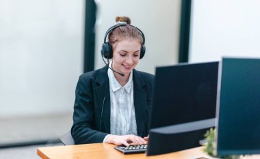 İş kadını, rapor üzerinde çalışırken masasında oturuyor. Modern ofis ortamı, bilgisayar ve düzenli çalışma alanı ile birlikte, verimliliği, verimliliği ve pozitif çalışma ortamını yansıtır..