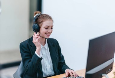 İş kadını, rapor üzerinde çalışırken masasında oturuyor. Modern ofis ortamı, bilgisayar ve düzenli çalışma alanı ile birlikte, verimliliği, verimliliği ve pozitif çalışma ortamını yansıtır..