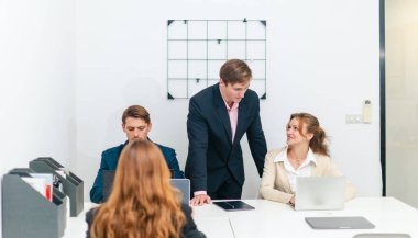 Diğer takım üyeleri toplantıya dikkatle katılırken, profesyonel iş adamları modern ofis ortamında dizüstü bilgisayarla bir tartışmaya giriştiler..