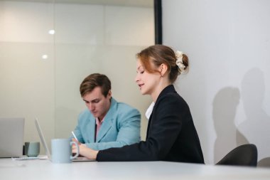 Diğer takım üyeleri toplantıya dikkatle katılırken, profesyonel iş adamları modern ofis ortamında dizüstü bilgisayarla bir tartışmaya giriştiler..