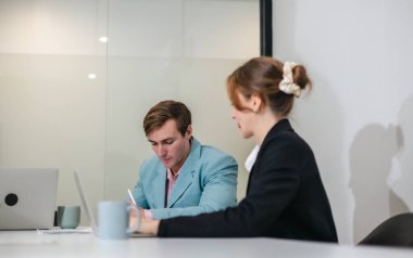 Diğer takım üyeleri toplantıya dikkatle katılırken, profesyonel iş adamları modern ofis ortamında dizüstü bilgisayarla bir tartışmaya giriştiler..