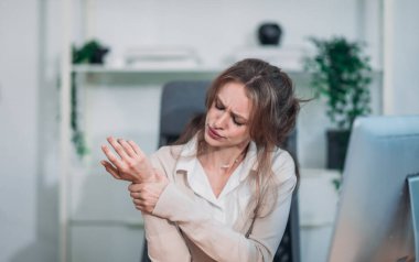 Geç saatlere kadar masa başında çalışırken ofis sendromu geçiren yorgun ve stresli bir iş kadını. Uzun saatler ve aşırı ekran süresi uzun çalışma saatlerinden dolayı fiziksel ve zihinsel yorgunluğa yol açar..