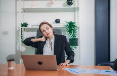 Geç saatlere kadar masa başında çalışırken ofis sendromu geçiren yorgun ve stresli bir iş kadını. Uzun saatler ve aşırı ekran süresi uzun çalışma saatlerinden dolayı fiziksel ve zihinsel yorgunluğa yol açar..