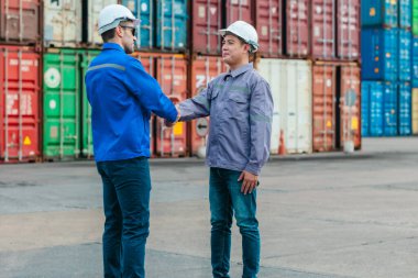 Farklı takımlardan lojistik işçileri, ikmal zinciri ve ulaşım sektöründe takım çalışması ve koordinasyon sergileyen bir nakliye konteynerinde işbirliği yapmaktadırlar..