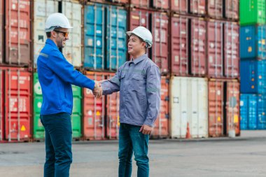 Farklı takımlardan lojistik işçileri, ikmal zinciri ve ulaşım sektöründe takım çalışması ve koordinasyon sergileyen bir nakliye konteynerinde işbirliği yapmaktadırlar..