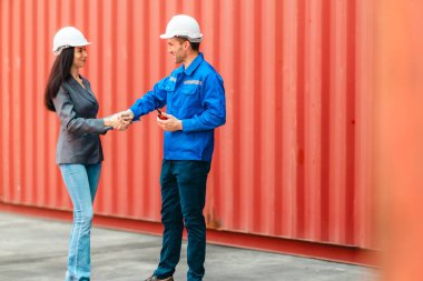 Farklı takımlardan lojistik işçileri, ikmal zinciri ve ulaşım sektöründe takım çalışması ve koordinasyon sergileyen bir nakliye konteynerinde işbirliği yapmaktadırlar..