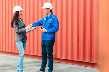 Farklı takımlardan lojistik işçileri, ikmal zinciri ve ulaşım sektöründe takım çalışması ve koordinasyon sergileyen bir nakliye konteynerinde işbirliği yapmaktadırlar..