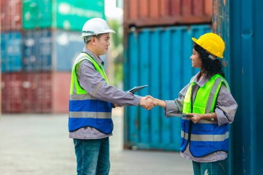 Farklı takımlardan lojistik işçileri, ikmal zinciri ve ulaşım sektöründe takım çalışması ve koordinasyon sergileyen bir nakliye konteynerinde işbirliği yapmaktadırlar..
