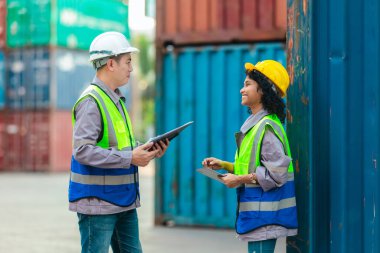 Farklı takımlardan lojistik işçileri, ikmal zinciri ve ulaşım sektöründe takım çalışması ve koordinasyon sergileyen bir nakliye konteynerinde işbirliği yapmaktadırlar..