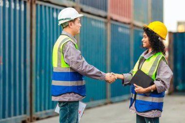 Farklı takımlardan lojistik işçileri, ikmal zinciri ve ulaşım sektöründe takım çalışması ve koordinasyon sergileyen bir nakliye konteynerinde işbirliği yapmaktadırlar..