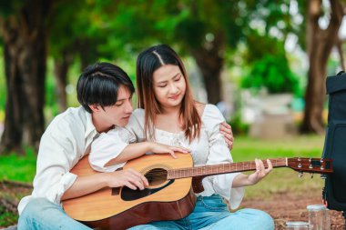 Asyalı bir çift göl kenarında barışçıl bir pikniğin keyfini çıkarırken, akustik gitar çalan bir adam da birbirlerine sıcak bir şekilde bağlanıyorlar. Doğal ortamdaki romantik ve müzikal bir an..