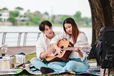 Asyalı bir çift göl kenarında barışçıl bir pikniğin keyfini çıkarırken, akustik gitar çalan bir adam da birbirlerine sıcak bir şekilde bağlanıyorlar. Doğal ortamdaki romantik ve müzikal bir an..