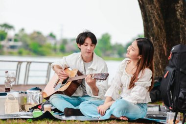 Asyalı bir çift göl kenarında barışçıl bir pikniğin keyfini çıkarırken, akustik gitar çalan bir adam da birbirlerine sıcak bir şekilde bağlanıyorlar. Doğal ortamdaki romantik ve müzikal bir an..