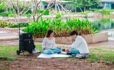 Asyalı bir çift parkta piknik minderinde oturmuş satranç oynarken rahat bir anın tadını çıkarıyor. Atmosfer sakin ve samimi. Strateji, bağlantı ve kaliteli zaman karışımını yakalıyor.