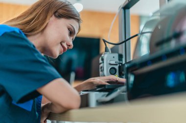 Mühendis, ileri üretim ve prototip teknolojisi sergileyen bir atölyede yeni basılmış üç boyutlu bileşenleri inceliyor. Yenilikleri yansıtan, hassas mühendislik, endüstriyel tasarım süreçleri