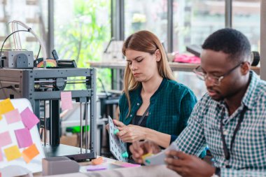 Girişimci profesyonellerden oluşan çeşitli bir ekip, modern bir çalışma alanında üç boyutlu bir baskı projesi üzerinde işbirliği yapmaktadır. Yaratıcı bir teknoloji ortamında yenilik, takım çalışması ve prototipleme sürecinin altını çizmek.