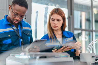 3D yazıcının yanında dikilirken mühendisler renk örnekleme kılavuzunu gözden geçirir, geri dönüşümlü 3D yazdırılmış ürünler için renk seçerler. Üretim süreçlerinde yaratıcılık, sürdürülebilirlik ve kesinliğin vurgulanması