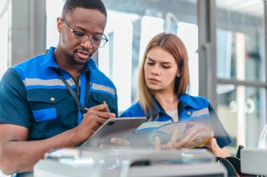 3D yazıcının yanında dikilirken mühendisler renk örnekleme kılavuzunu gözden geçirir, geri dönüşümlü 3D yazdırılmış ürünler için renk seçerler. Üretim süreçlerinde yaratıcılık, sürdürülebilirlik ve kesinliğin vurgulanması