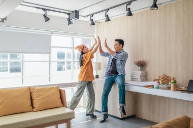 Takım üyeleri modern ofis ortamında başarılı bir projeyi coşkuyla kutluyorlar. Takım çalışmasını, motivasyonu ve başlangıç ortamında hedeflere ulaşmanın sevincini yakaladığınız an.