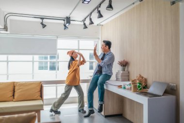 Takım üyeleri modern ofis ortamında başarılı bir projeyi coşkuyla kutluyorlar. Takım çalışmasını, motivasyonu ve başlangıç ortamında hedeflere ulaşmanın sevincini yakaladığınız an.