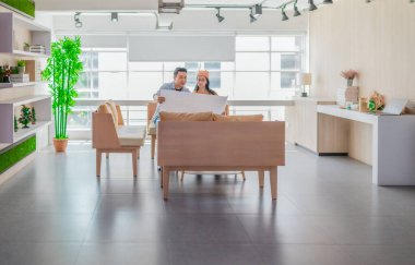 İki profesyonel, parlak ve modern bir çalışma alanında büyük bir planlama tablosunu gözden geçiriyorlar. Sahne, bir başlangıç ortamında takım çalışması, stratejik düşünme ve işbirlikçi proje gelişimini yansıtıyor