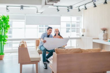 İki profesyonel, parlak ve modern bir çalışma alanında büyük bir planlama tablosunu gözden geçiriyorlar. Sahne, bir başlangıç ortamında takım çalışması, stratejik düşünme ve işbirlikçi proje gelişimini yansıtıyor