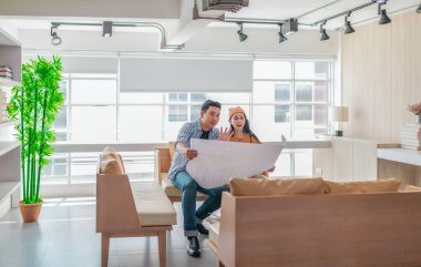 İki profesyonel, parlak ve modern bir çalışma alanında büyük bir planlama tablosunu gözden geçiriyorlar. Sahne, bir başlangıç ortamında takım çalışması, stratejik düşünme ve işbirlikçi proje gelişimini yansıtıyor