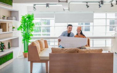 İki profesyonel, parlak ve modern bir çalışma alanında büyük bir planlama tablosunu gözden geçiriyorlar. Sahne, bir başlangıç ortamında takım çalışması, stratejik düşünme ve işbirlikçi proje gelişimini yansıtıyor