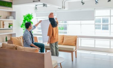 İki profesyonel, parlak ve modern bir çalışma alanında büyük bir planlama tablosunu gözden geçiriyorlar. Sahne, bir başlangıç ortamında takım çalışması, stratejik düşünme ve işbirlikçi proje gelişimini yansıtıyor