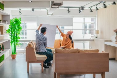 İki profesyonel, parlak ve modern bir çalışma alanında büyük bir planlama tablosunu gözden geçiriyorlar. Sahne, bir başlangıç ortamında takım çalışması, stratejik düşünme ve işbirlikçi proje gelişimini yansıtıyor